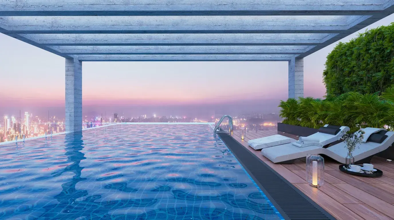 A rooftop infinity pool at dusk with sun loungers and a distant city skyline