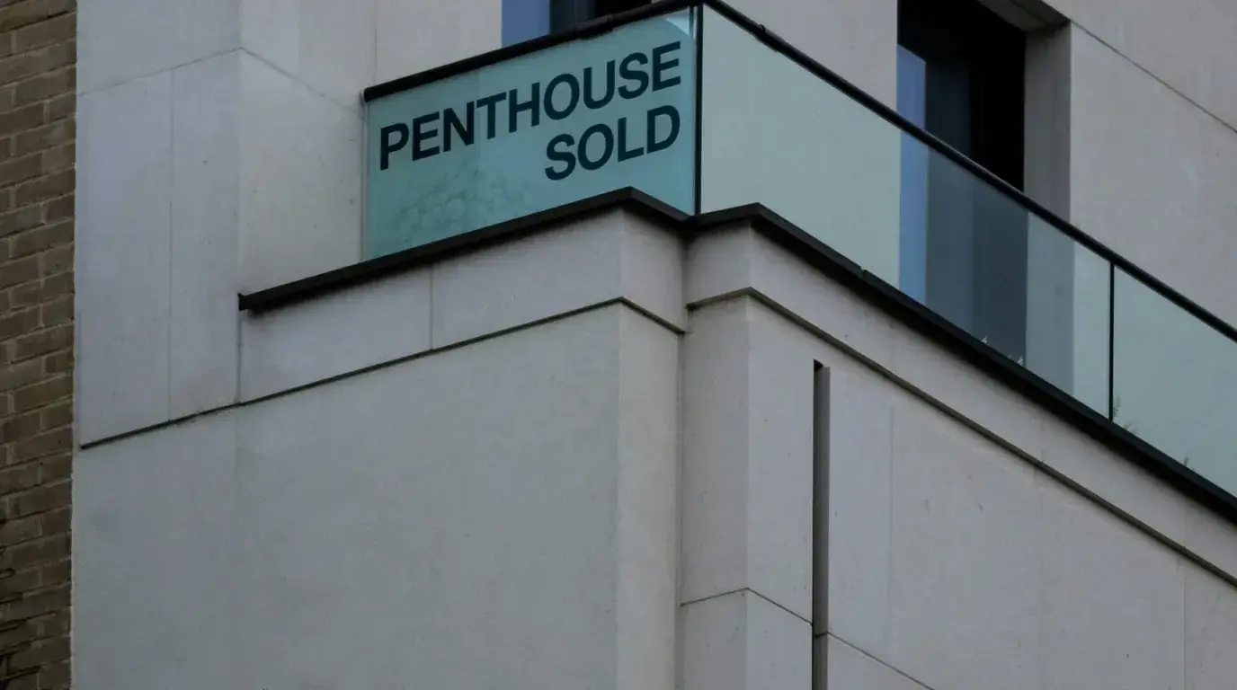 A glass balcony sign reading PENTHOUSE SOLD on a pale concrete building