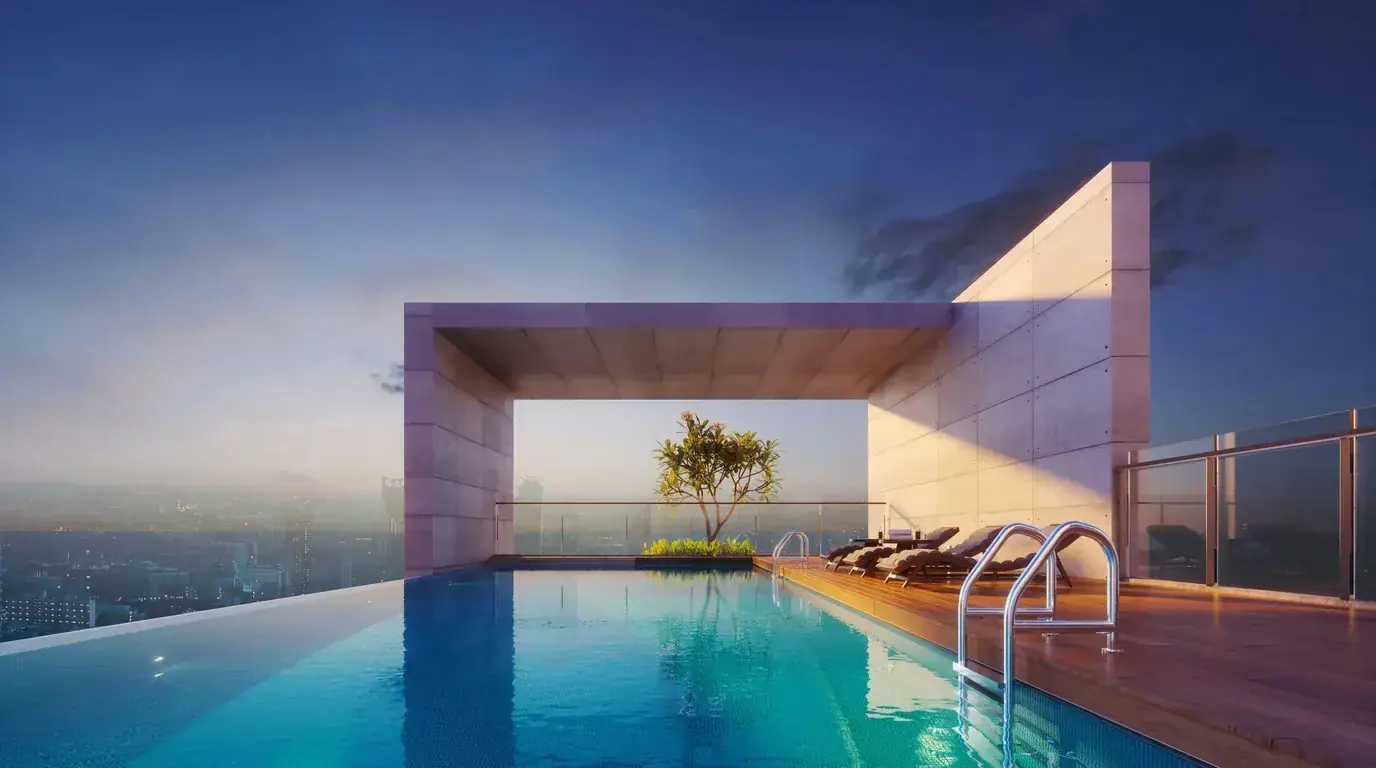 A rooftop pool beside a pink stone pavilion with a single planted tree